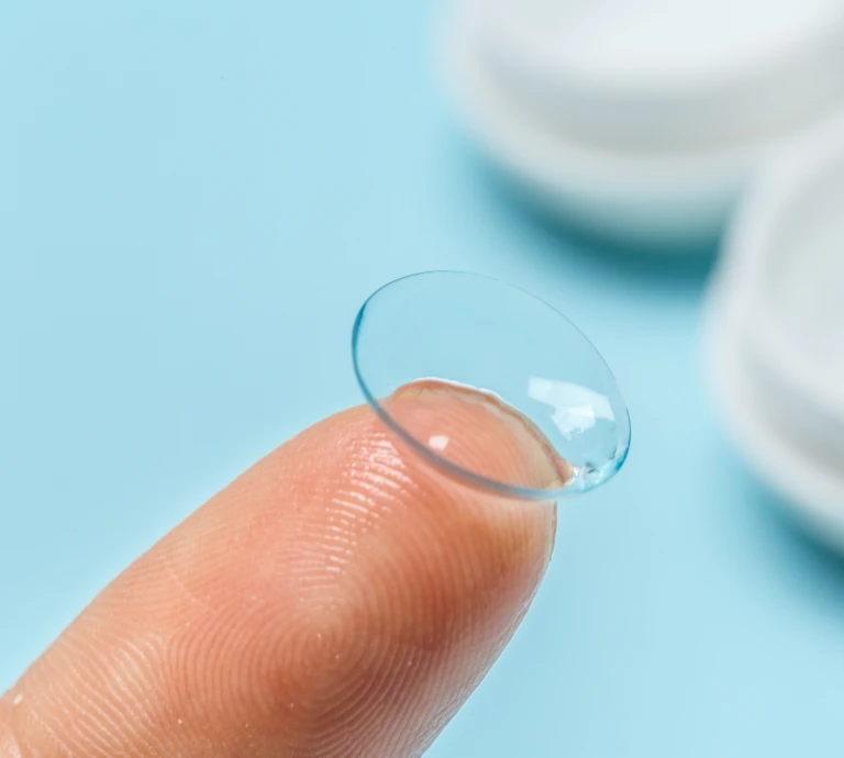 Close-up of a soft contact lens resting on a fingertip, illustrating proper handling before insertion.