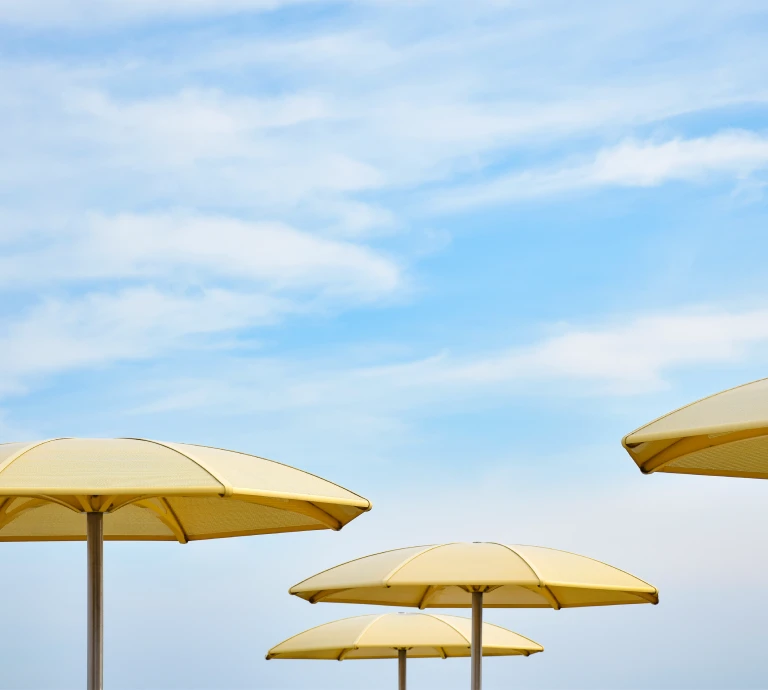 Yellow parasols against a blue sky background with light clouds.